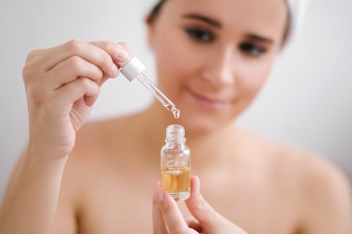 Woman holding dropper with jojoba oil